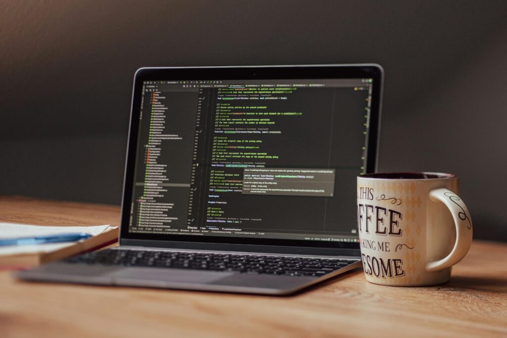 What's VirtuaGro Laptop displaying code editor with coffee mug on desk, perfect for tech themes.